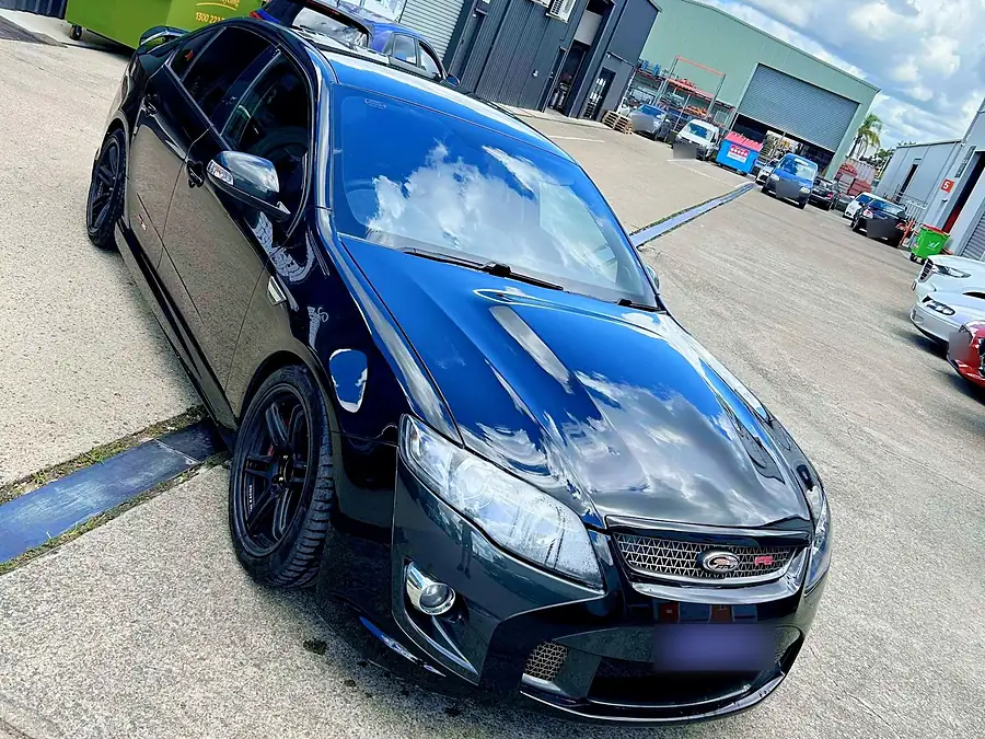 Black sedan with a mirror gloss bonnet reflecting the clouds