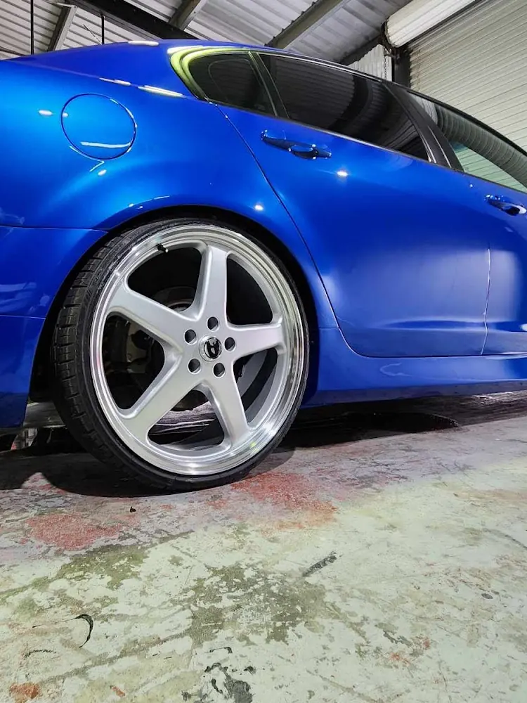 Close-up of a blue sedan's rear quarter panel and polished silver wheel